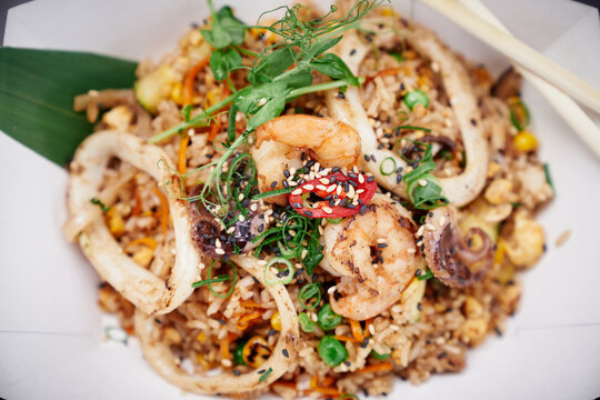 Chinese healthy fast food. Top view of fried rice with seafood and vegetables prepared in Chinese wok as vegetarian food concept. Shrimps, squid and octopus with rice stir fry. High quality image
