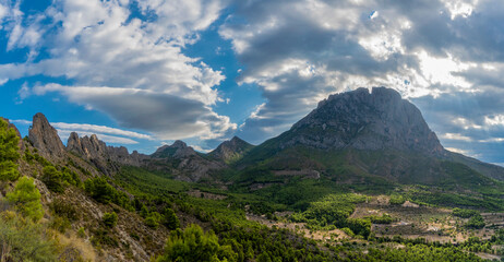 Naklejka na ściany i meble mountains and a beautiful sky with rays of sun over the mountain Puig Campana. Mount Castellet on the left. Landscape located in Finestrat, located in the Valencian Community, Alicante, Spain