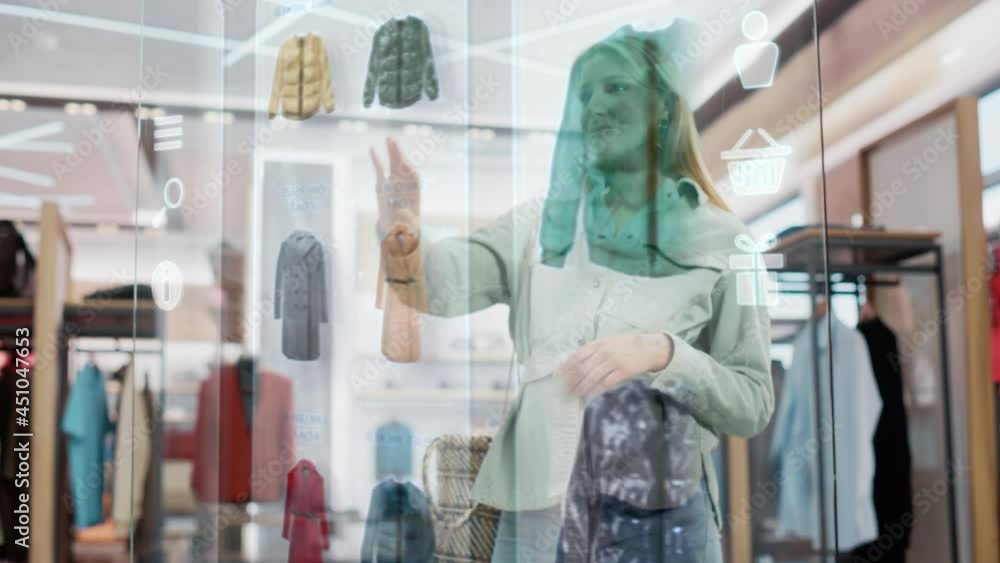 Wall mural Beautiful Female Customer Using 3D Augmented Reality Digital Interface in Modern Shopping Center. Shopper is Choosing Fashionable Bags, Stylish Garments in Clothing Store. Futuristic VFX UI Concept.