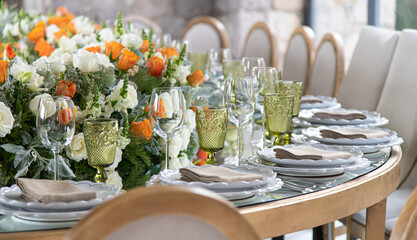 Mesa de boda con flores naranja cristalería verde.