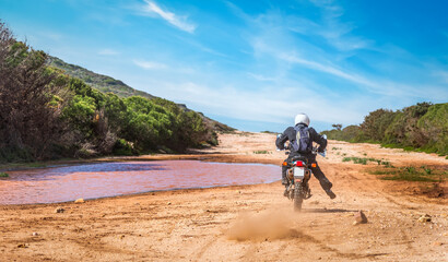 Man riding an adventure bike on a dirt road under