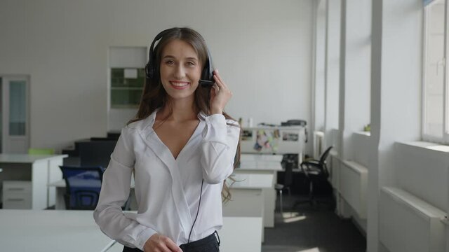 Young woman stands and holds her black headphones