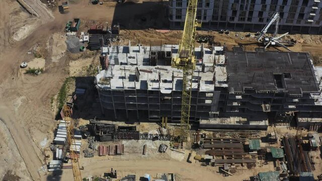 Aerial Flight Over a New Constructions Development Site with High Tower Cranes Building Real Estate. Heavy Machinery and Construction Workers are Employed. Urban Construction Site, Aerial View