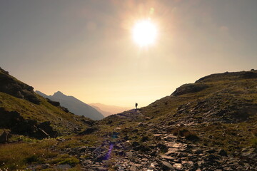 Naklejka premium Small silhouette of tourist with backpack on the rocky mountain slope. Beauty of nature, tourism and travel concept