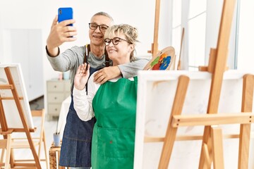 Two senior paint student smiling happy making selfie by the smartphone at art studio.