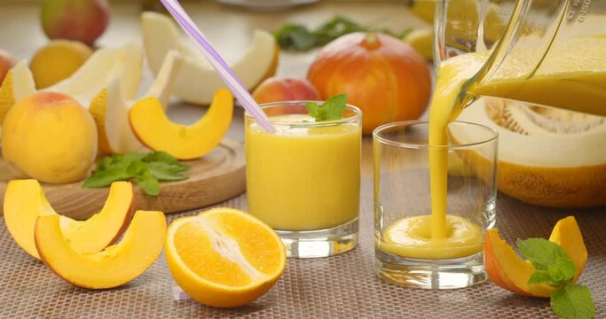 Melon banana orange Smoothie is poured into a glass on the background of fresh fruits