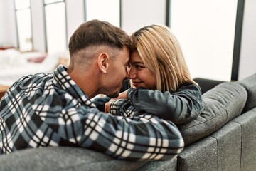 Young caucasian couple smiling happy sitting on the sofa at home.