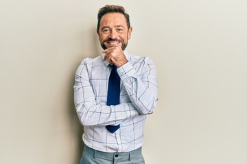 Middle age businessman wearing business shirt and tie smiling looking confident at the camera with crossed arms and hand on chin. thinking positive.