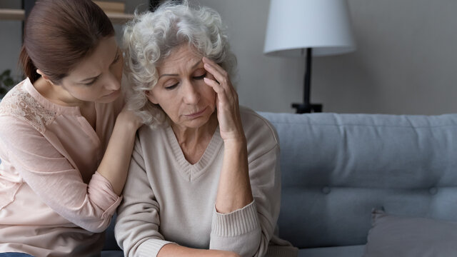 Caring adult grownup daughter comfort caress unhappy sad middle-aged Caucasian 60s mother mourning yearning. Loving supportive woman child support hug upset old mom feeling bad distressed.