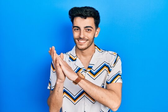 Young hispanic man wearing casual clothes clapping and applauding happy and joyful, smiling proud hands together