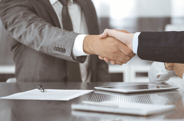 Handshake as successful negotiation ending, close-up. Unknown business people shaking hands after contract signing in modern office