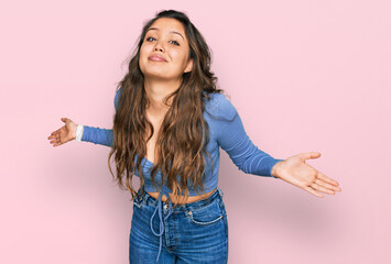 Young hispanic girl wearing casual clothes clueless and confused expression with arms and hands...
