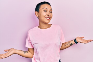 Beautiful hispanic woman with short hair wearing casual pink t shirt smiling showing both hands open palms, presenting and advertising comparison and balance