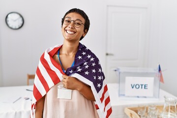 Young hispanic woman with short hair at political campaign election holding usa flag looking...