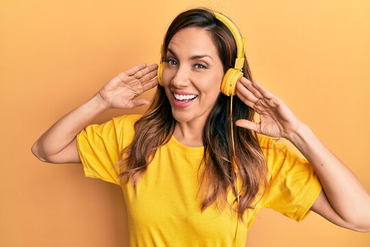 Young latin woman listening to music using headphones celebrating crazy and amazed for success with open eyes screaming excited.