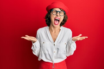 Young brunette woman wearing stewardess style and glasses celebrating mad and crazy for success...
