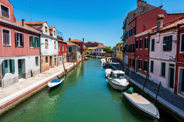 Fototapeta na wymiar Beautiful houses and boats along a narrow canal in Venice, Italy.