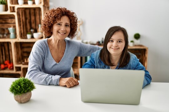 Mature mother and down syndrome daughter using computer laptop at home