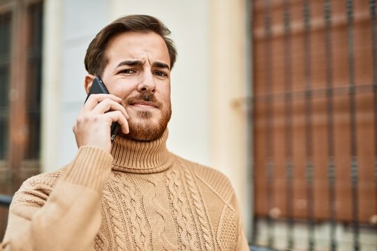 Young caucasian man with serious expression talking on the smartphone at the city.