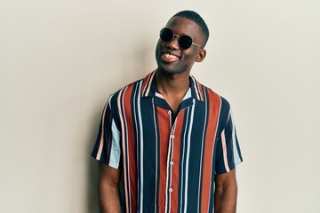 Young african american man wearing casual clothes and sunglasses looking to side, relax profile...
