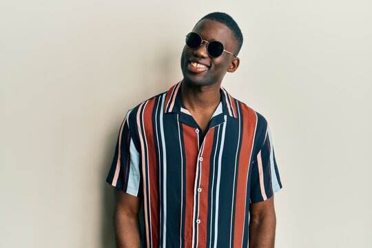Young african american man wearing casual clothes and sunglasses looking to side, relax profile pose with natural face and confident smile.