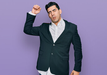 Handsome hispanic man wearing business clothes stretching back, tired and relaxed, sleepy and yawning for early morning