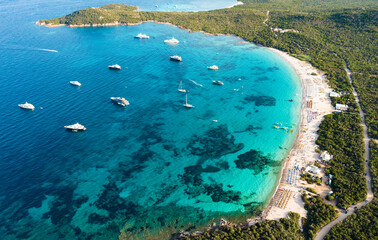 View from above, stunning aerial view of a green coastline with a white sand beach and and boats...