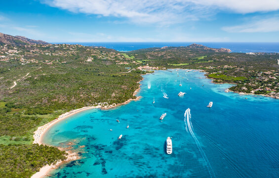 View from above, stunning aerial view of the Cala di volpe bay with a green coastline, white sand beaches and luxury yachts sailing on a turquoise water. Liscia Ruja,Sardinia, Italy.