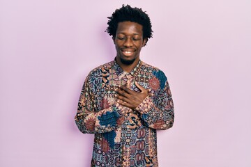 Young african american man wearing casual clothes smiling with hands on chest with closed eyes and grateful gesture on face. health concept.