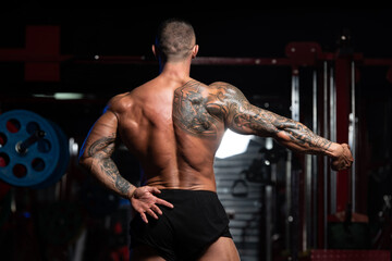 Fototapeta na wymiar Muscular Man Flexing Muscles In Gym