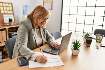Middle age businesswoman smiling happy working at the office.