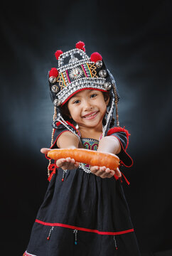 A hill tribe girl holding a carrot.