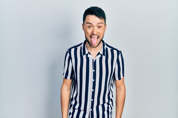 Fototapeta premium Young hispanic man wearing casual clothes sticking tongue out happy with funny expression. emotion concept.