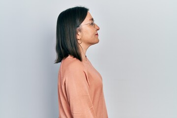 Middle age hispanic woman wearing casual clothes and glasses looking to side, relax profile pose...