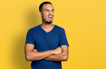 Young african american man with arms crossed gesture angry and mad screaming frustrated and...