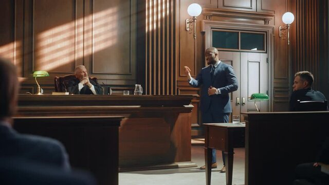 Court of Law Trial in Session: Portrait of Charismatic Male Public Defender Making Touching, Passionate Speech to Judge and Jury. Attorney Lawyer Protecting Client, Presenting Case.