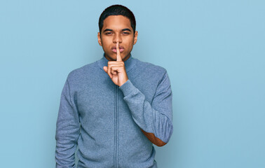 Young handsome hispanic man wearing casual sweatshirt asking to be quiet with finger on lips....