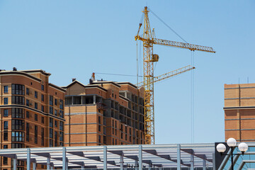 Tower crane and reinforced building under construction project site against blue sky.