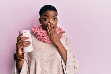 Young african american woman wearing winter scarf and drinking hot take away coffee covering mouth...