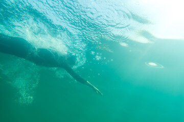 Athlete in a wetsuit swims in a lake