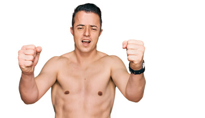 Handsome young man wearing swimwear shirtless angry and mad raising fists frustrated and furious while shouting with anger. rage and aggressive concept.