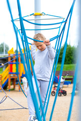 Little girl climbing in an adventure park. The girl loves to climb in the adventure of the rope course. Little girl on the rope obstacle course