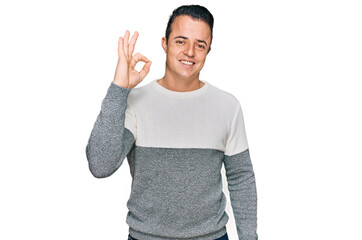 Handsome young man wearing casual winter sweater smiling positive doing ok sign with hand and fingers. successful expression.