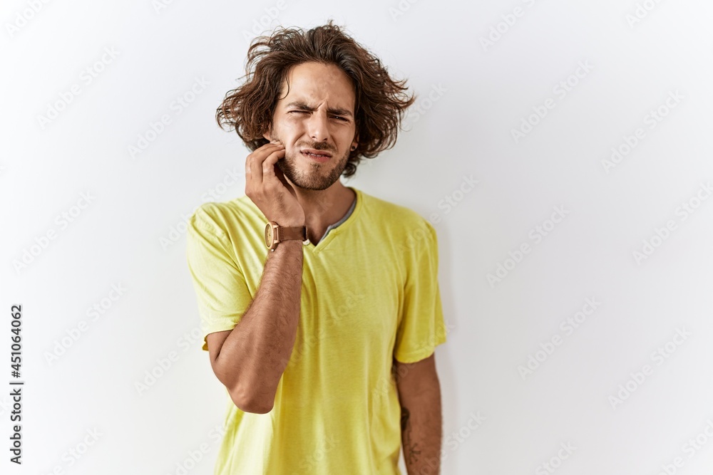 Sticker young hispanic man standing over isolated background touching mouth with hand with painful expressio