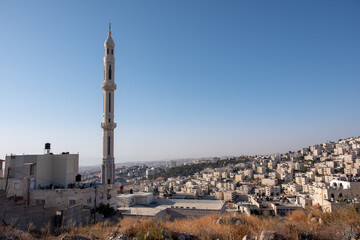The exceptionally high Minaret of Khalid ibn Al-Walid Mosque, located in At-Tur, an Arab-majority neighborhood on the Mount of Olives. East Jerusalem is on the background.