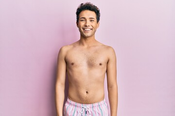 Fototapeta premium Young handsome man wearing swimwear shirtless with a happy and cool smile on face. lucky person.