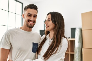 Young hispanic couple smiling happy and hugging at new home.