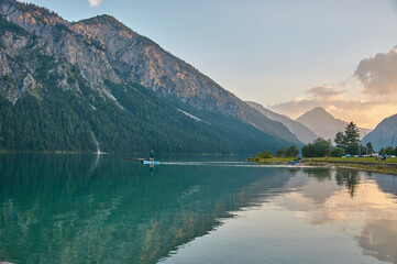 Stand up paddling in a beautiful mountain lake during sunset.