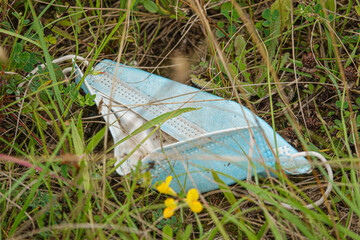 a modern rubbish problem; a discarded Covid-19 face mask thrown away in the grass 