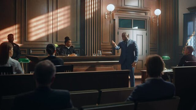Court of Law Trial in Session: Portrait of Charismatic Male Public Defender Making Touching, Passionate Speech to Judge and Jury. Attorney Lawyer Protecting Client, Presenting Case.